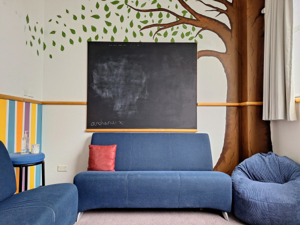 The quiet room features plush seating, a blackboard, and a mural of a tree.